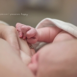 This newborn retracts her long graceful fingers in a moment of breastfeeding bliss.